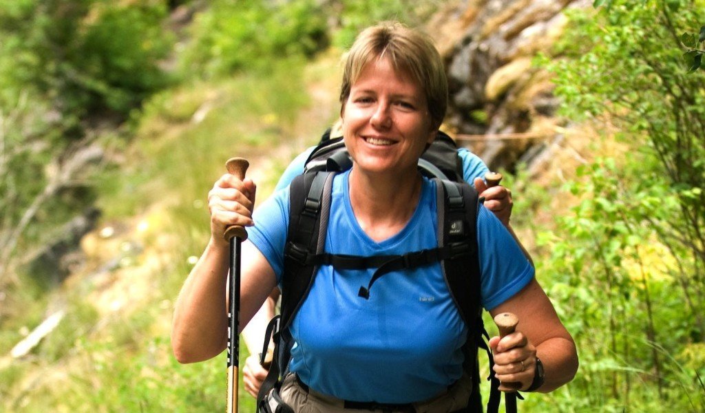 Close-up of a woman hiking with poles and backpack