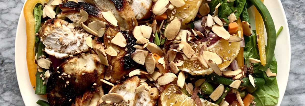 salad with chicken and almonds on plate with marble background