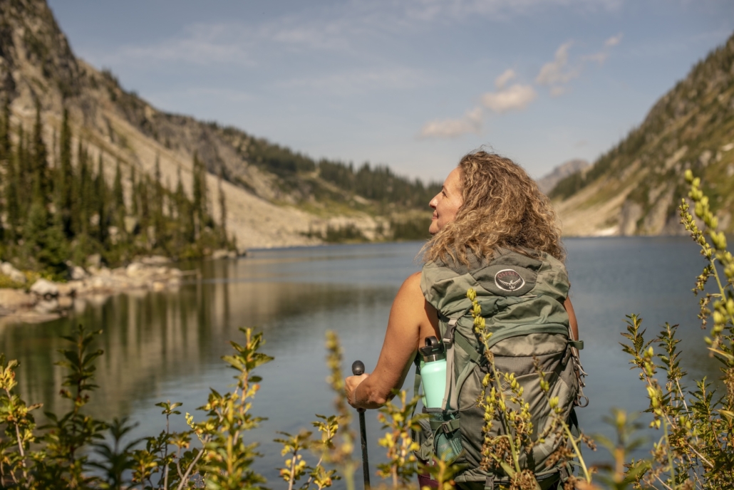 Hiker savors sun on her face overlooking an alpine lake while at Mountain Trek Health Reset Retreat