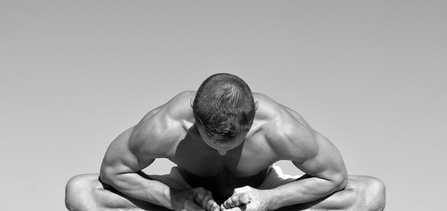 Strong Man Practicing Yoga bend over grabbing toes