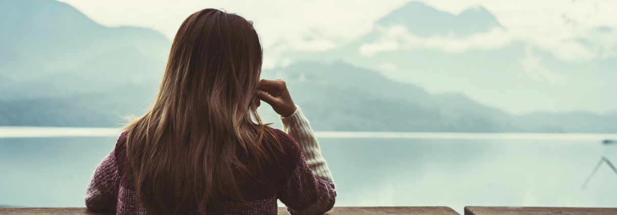 Lonely woman standing absent minded and looking at the river