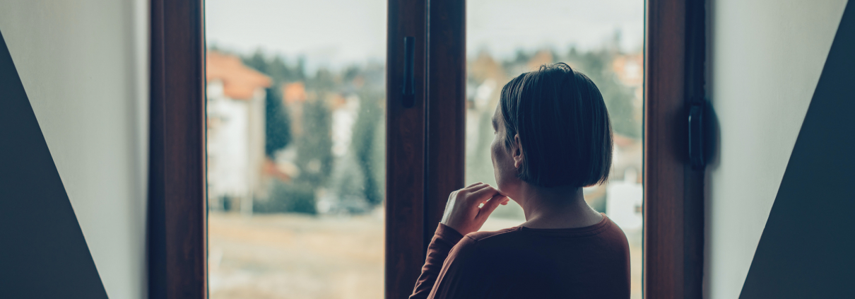 Sad woman looking out of the window in loft apartment