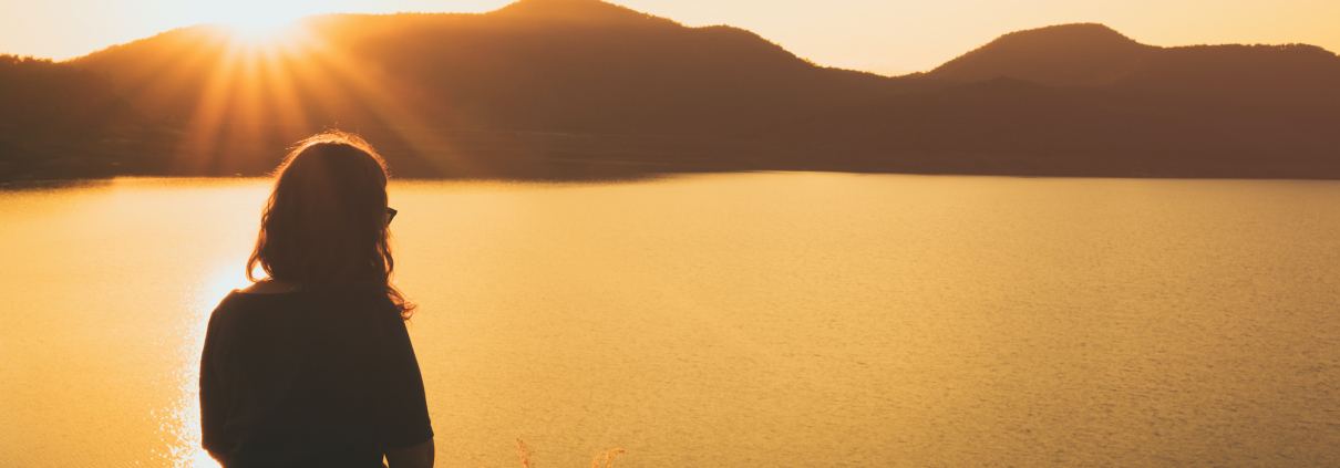 a woman Relaxing, sitting overlooking a lake and mountains