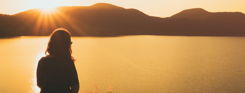 a woman Relaxing, sitting overlooking a lake and mountains